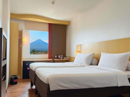 two beds in a hotel room with a view of a mountain at Ibis Bandung Pasteur in Bandung