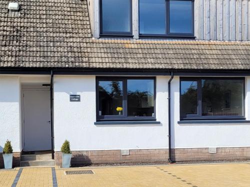 a white building with windows and a door at Colbheinn Cottage in Brora