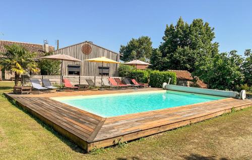 a pool with a wooden deck and chairs and a house at Superbe Maison Avec Piscine in Mombrier