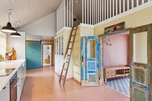 une pièce ouverte avec une porte ouverte et une échelle dans l'établissement Stråtækt feriehusidyl ved vandet, à Sønderborg