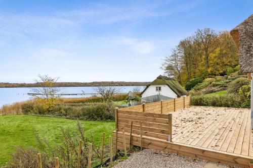 a wooden deck next to a body of water at Stråtækt feriehusidyl ved vandet in Sønderborg