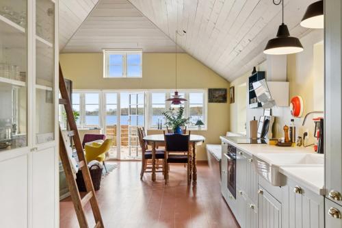 a kitchen and dining room with a table and chairs at Stråtækt feriehusidyl ved vandet in Sønderborg
