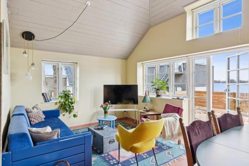 a living room with a blue couch and chairs at Stråtækt feriehusidyl ved vandet in Sønderborg
