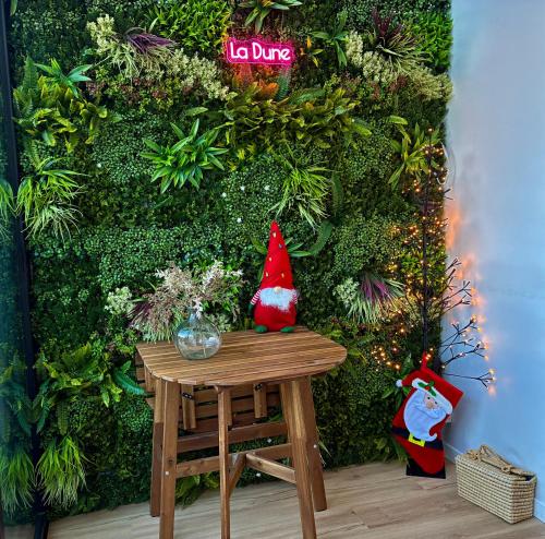 Eine Weihnachtsmannfigur sitzt auf einem Tisch vor einer grünen Wand in der Unterkunft DUNE Océan Luxe Appartement, Accès Plage privé, Parking & Wifi 50m Océan Surf in Seignosse