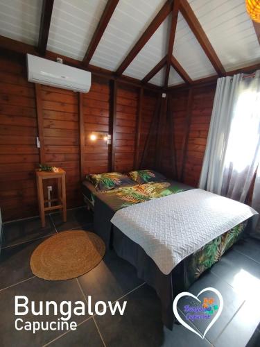 a bedroom with two beds in a wooden room at Bungalow Capucine in Capesterre-Belle-Eau