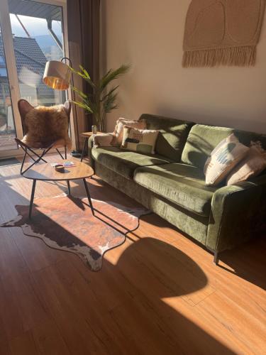 ein Wohnzimmer mit einer grünen Couch und einem Tisch in der Unterkunft Vista Izera in Świeradów-Zdrój