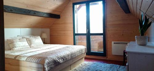 une chambre avec un lit et une grande fenêtre dans l'établissement House Planinka in the heart of nature, à Ljubno