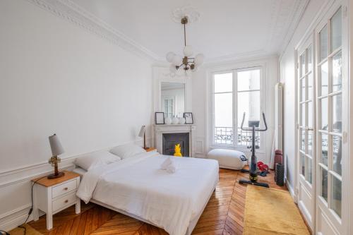 ein weißes Schlafzimmer mit einem Bett und einem Kamin in der Unterkunft Parisian Escape and Jacuzzi and green Vibes in Paris