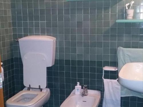 uma casa de banho com azulejos verdes, um WC e um lavatório. em La Pizzerella di Amalfi em Amalfi