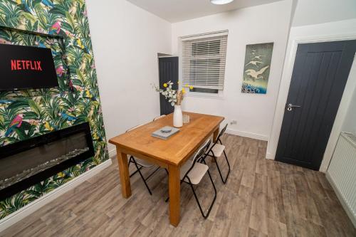 ein Esszimmer mit einem Holztisch und einem Kamin in der Unterkunft Pitchside Comfort – 3-Bed Swansea Home in Morriston
