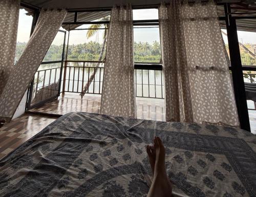 a persons feet on a bed with a view at RivoGoa riverside Homestay in Bardez