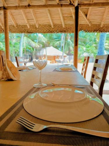 una mesa con un plato y copas de vino. en Coco Cottage Kite Surfing-Kalpitiya, en Kandakuli