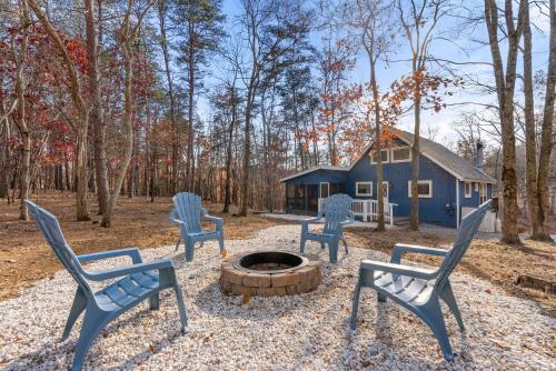 a group of chairs around a fire pit in front of a blue house at Dog-Friendly Chalet in The Woods Resort w Fire Pit in Baxter