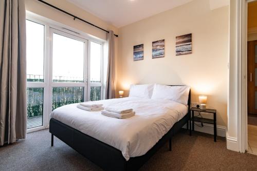 una camera da letto con un letto e una grande finestra di Stylish 2 Bed Flat with Free Parking near Harbour a Folkestone