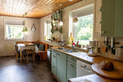 una cocina con armarios verdes y una mesa. en Stilbjerg Sleep&Hygge, en Varde