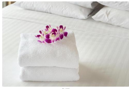 a white towel with purple flowers on a bed at Javelin Palace Hotel in Kampala