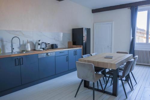 a kitchen with a wooden table and blue cabinets at Les Haussmanniens in Pont-de-Vaux