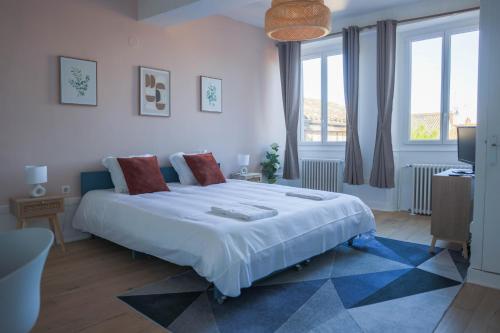 a bedroom with a large white bed and windows at Les Haussmanniens in Pont-de-Vaux