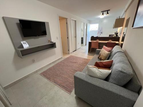 ein Wohnzimmer mit einem grauen Sofa und einem TV in der Unterkunft Puerto Ventura 403 · Puerto Ventura - Beira Mar na Orla de Cabo Branco in Tambaú