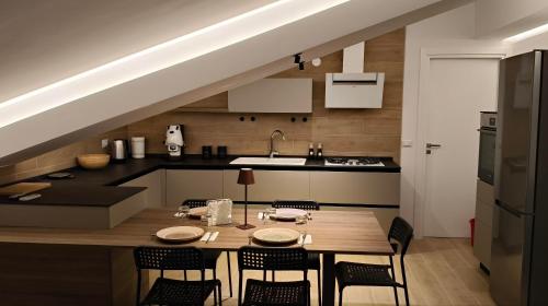 una cocina con mesa y sillas y una cocina debajo de una escalera en Lumeriam Sea Loft, en Roccalumera