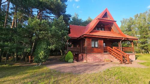 a log cabin with a red roof at Magiczny Dom nad Bugiem 