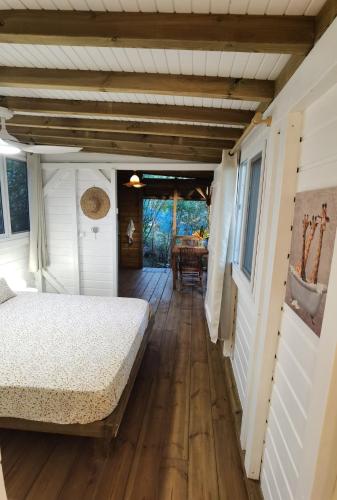 a bedroom with a bed and a wooden floor at Kaz Coco Bungalow in Bouillante