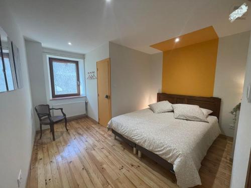 a bedroom with a bed and a chair and a window at Gîte La Chaumine in Brangues