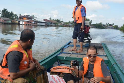 a group of three men on a boat on the water at Maena Water Chalets in Tumpat
