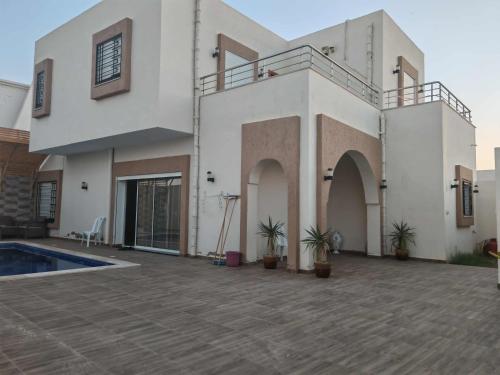 ein großes weißes Haus mit Topfpflanzen davor in der Unterkunft Villa shadow in Mezraya