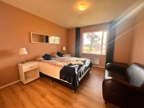 a bedroom with a bed and a couch and a window at Hlíðarból Guesthouse in Hvolsvöllur
