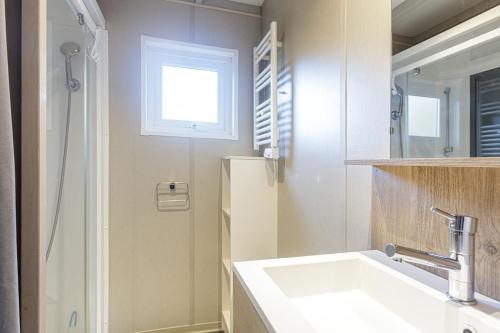 ein Badezimmer mit einem Waschbecken, einem Fenster und einem Spiegel in der Unterkunft Chalet 809 tout confort en lisière de forêt in La Teste-de-Buch