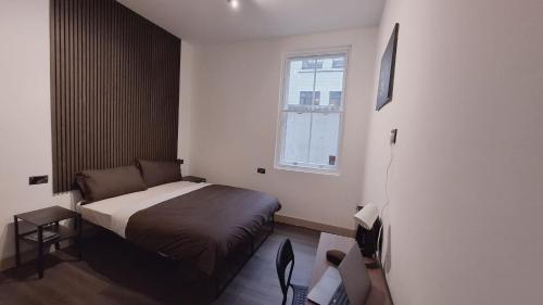 een kleine slaapkamer met een bed en een raam bij London Grand in Londen