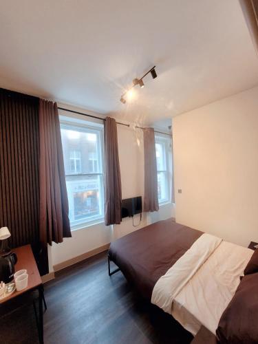 a bedroom with a bed and two windows at London Grand in London