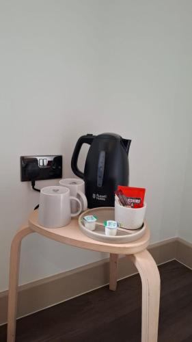 a table with a coffee pot and cups on it at London Grand in London
