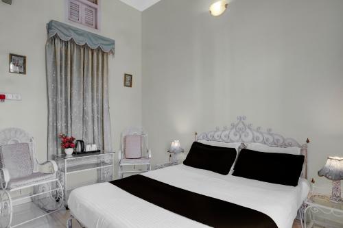 une chambre blanche avec un lit blanc avec des oreillers noirs dans l'établissement Hotel O Baruah Bhavan By Axom Inn Heritage, à Guwahati