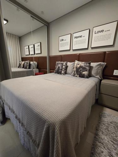 une chambre avec un grand lit et un miroir dans l'établissement Apartamento Reserva das Orquídeas, à Gramado