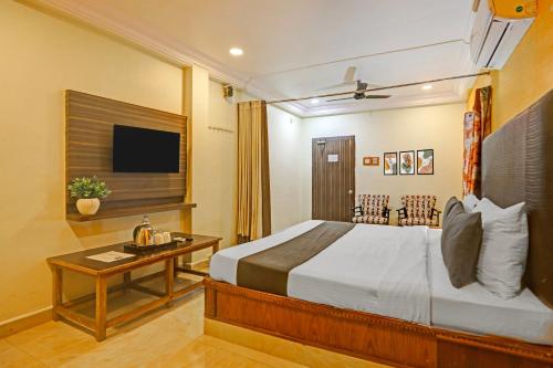 Un dormitorio con una cama, una mesa y un televisor. en Collection O Machilipatnam Bus Terminal Formerly Vijaya Raghava Residency, en Machilīpatnam