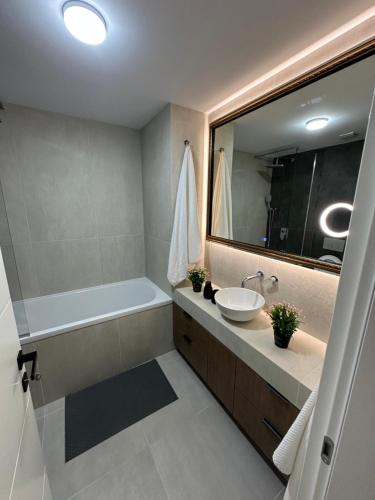 une salle de bain avec une baignoire, un lavabo et un miroir dans l'établissement Pipera Luxury Suite - Victoria Homes, à Voluntari