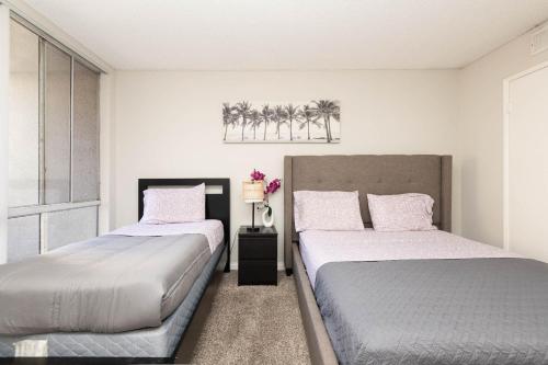two beds in a bedroom with palm trees on the wall at Hollywood Luxe 2BR Apartment with Rooftop Pool and Breathtaking Views in Los Angeles