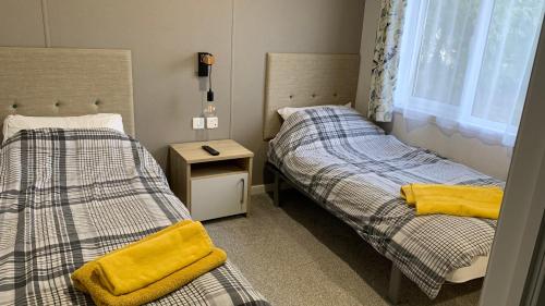 two beds in a small room with yellow towels at Grahams Lodge in Tydd Saint Giles
