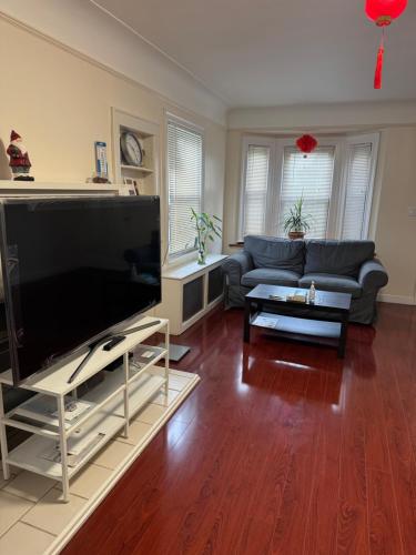 ein Wohnzimmer mit einem großen Flachbildfernseher in der Unterkunft 纽约 ZUHUA 长岛 Hofstra University霍夫斯特拉大学民宿 in Hempstead