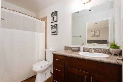 a bathroom with a sink and a toilet and a mirror at 2BR Hollywood Apt with Rooftop Pool & Stunning Views in Los Angeles