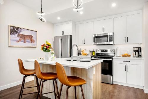 a kitchen with white cabinets and a kitchen island with chairs at New 2BR in DT Golden with AC, Balcony, BBQ, Sleeps 6 in Golden