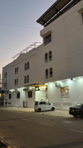 une voiture blanche garée devant un immeuble dans l'établissement Marigold hotel and restaurant, à Sialkot