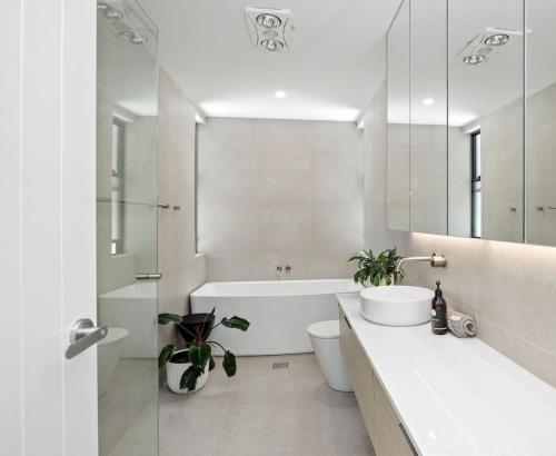 a bathroom with a tub and a toilet and a sink at Woodalla Way - Family Coastal Duplex Walk to Beach in Narrawallee