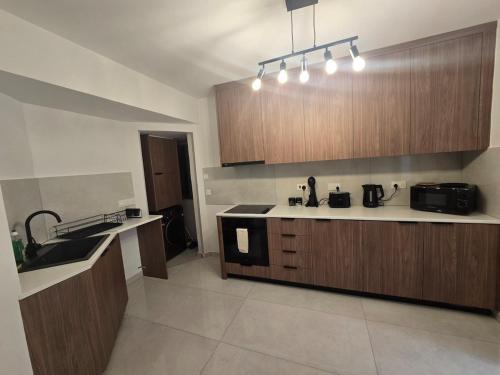 a kitchen with wooden cabinets and a sink at Maestro Family - Apartment in Larnaka