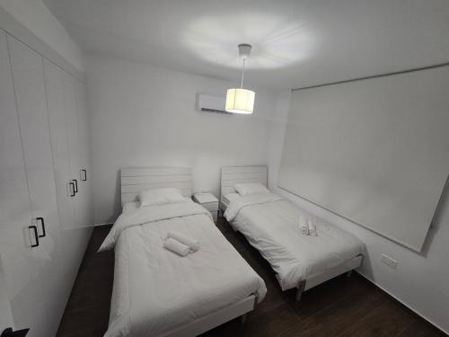two beds in a room with white walls at Maestro Family - Apartment in Larnaka