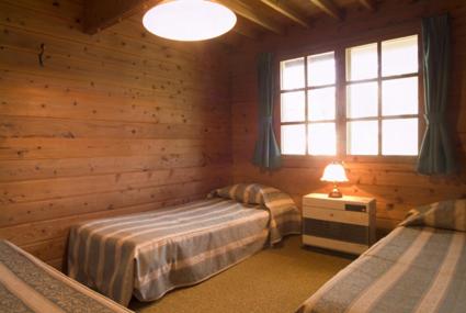 a bedroom with two beds in a log cabin at Pension Hana Kirin in Kitashiobara