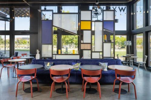 un ristorante con tavoli e sedie e un divano blu di Aloft Strasbourg City Centre a Strasburgo