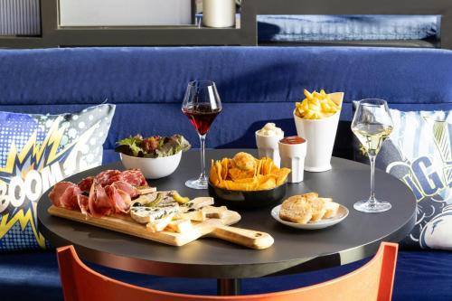 a table with a plate of food and glasses of wine at Aloft Strasbourg City Centre in Strasbourg